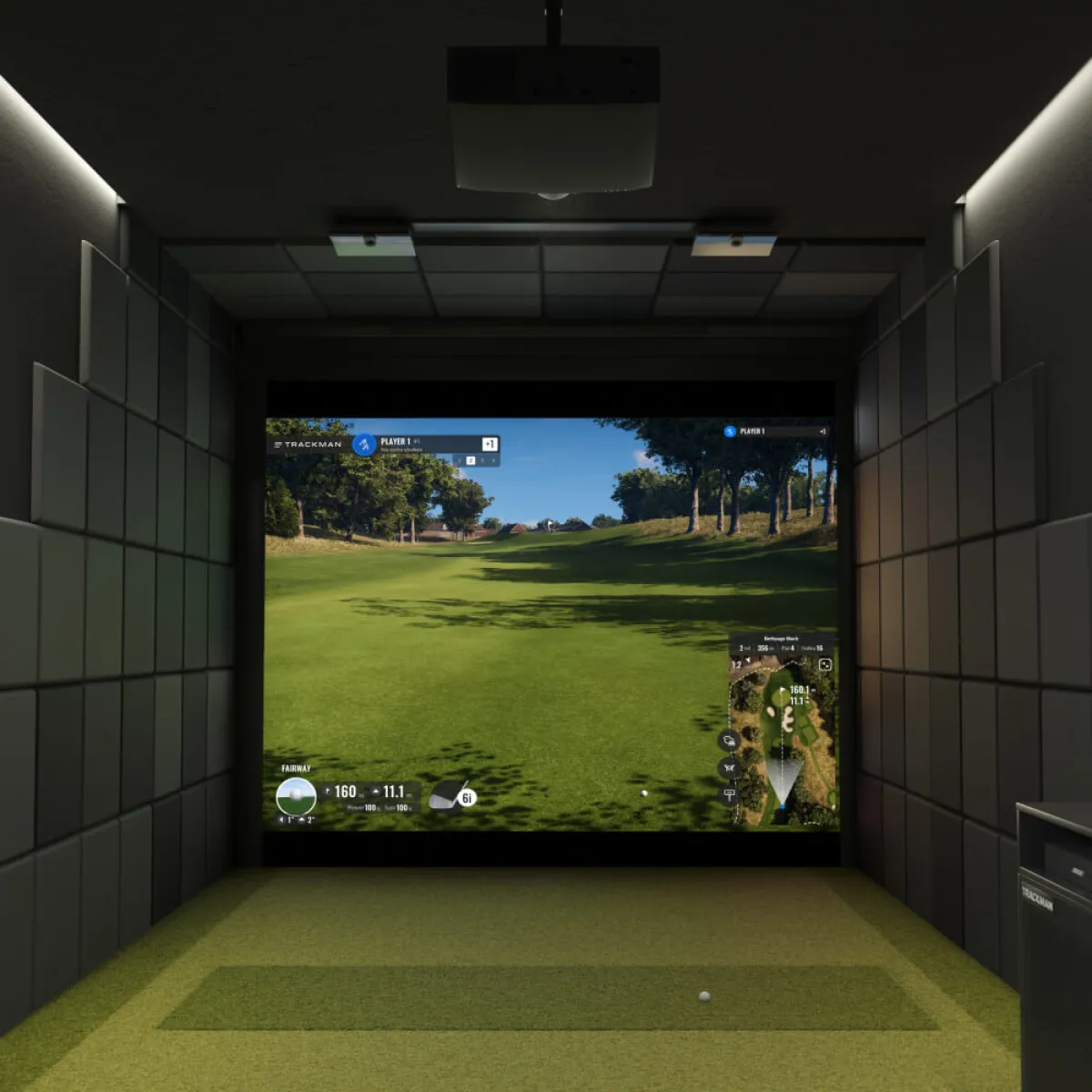 A TrackMan iO simulator — the ceiling-mounted unit above the hitting mat, course on screen